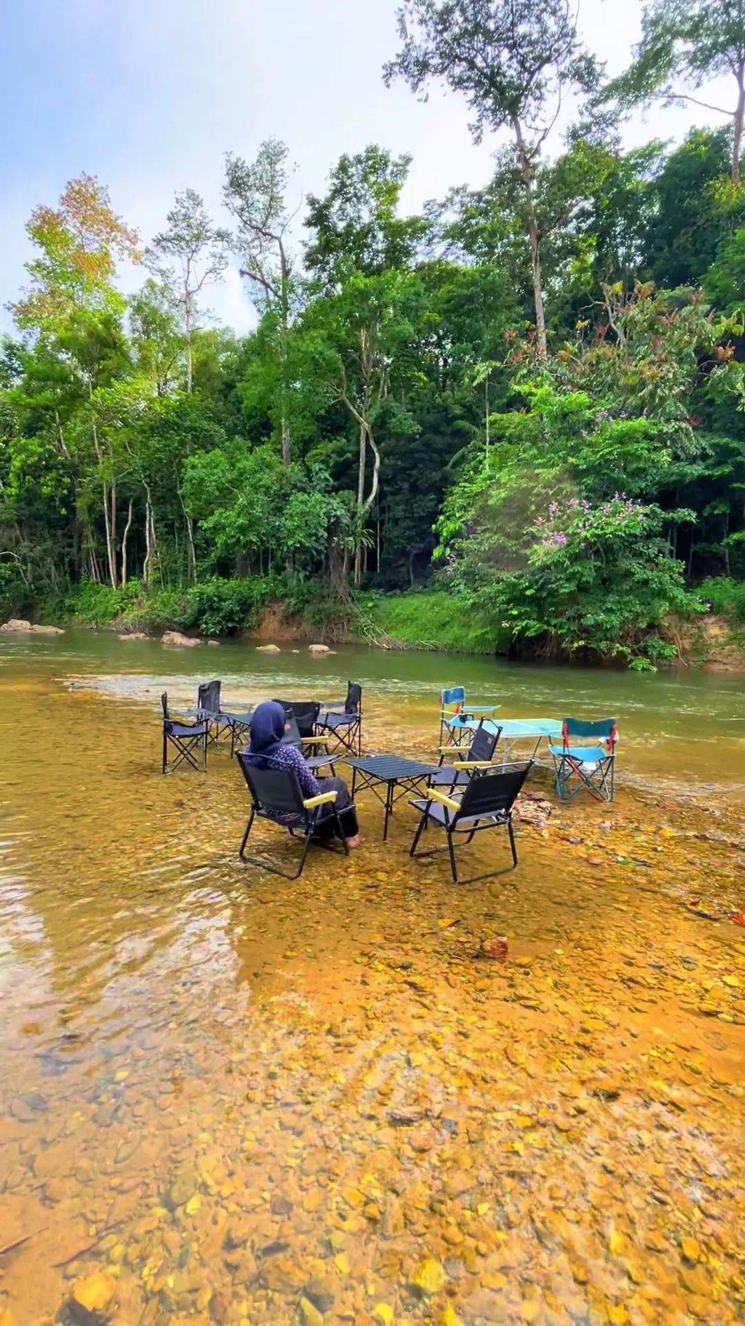 Kerusi lipat di dalam Sungai Lipis yang jernih, hutan di belakang